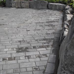 Pemberton patio of paving stones bordered by large natural rock boulders