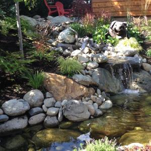 Patio sitting area beside a stone water feature and pond