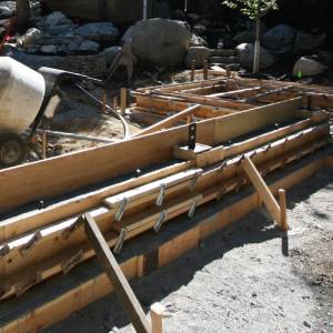 Crew pouring and mixing concrete into prepared forms on site